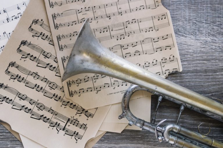 Notizbuch, Kaffeetasse und Trompete auf einem Tisch mit Notenblättern – stimmungsvolle Vorbereitung auf die Chorprobe im Klaukenhof