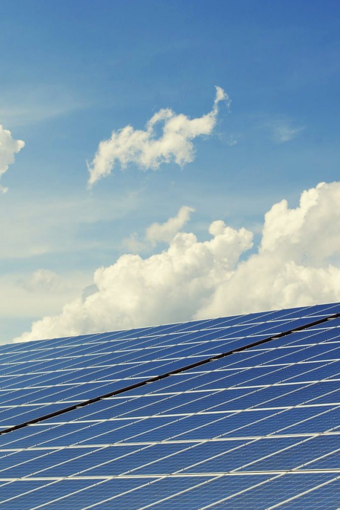 Sleek modern solar panels under a vibrant blue sky with clouds, symbolizing clean energy.