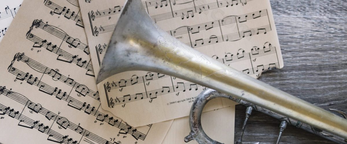 Notizbuch, Kaffeetasse und Trompete auf einem Tisch mit Notenblättern – stimmungsvolle Vorbereitung auf die Chorprobe im Klaukenhof